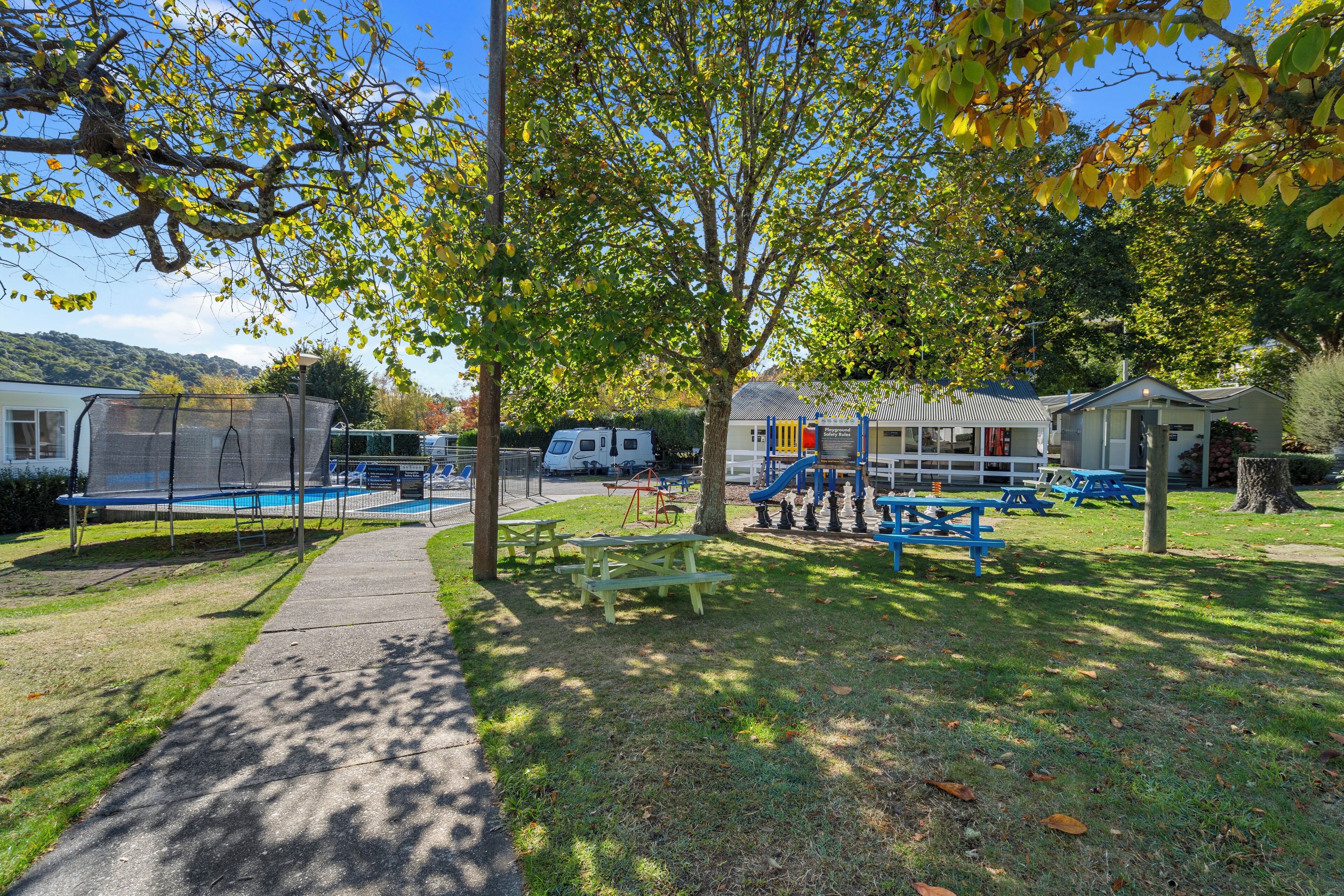 A park with picnic tables, a playground, and a swimming pool.