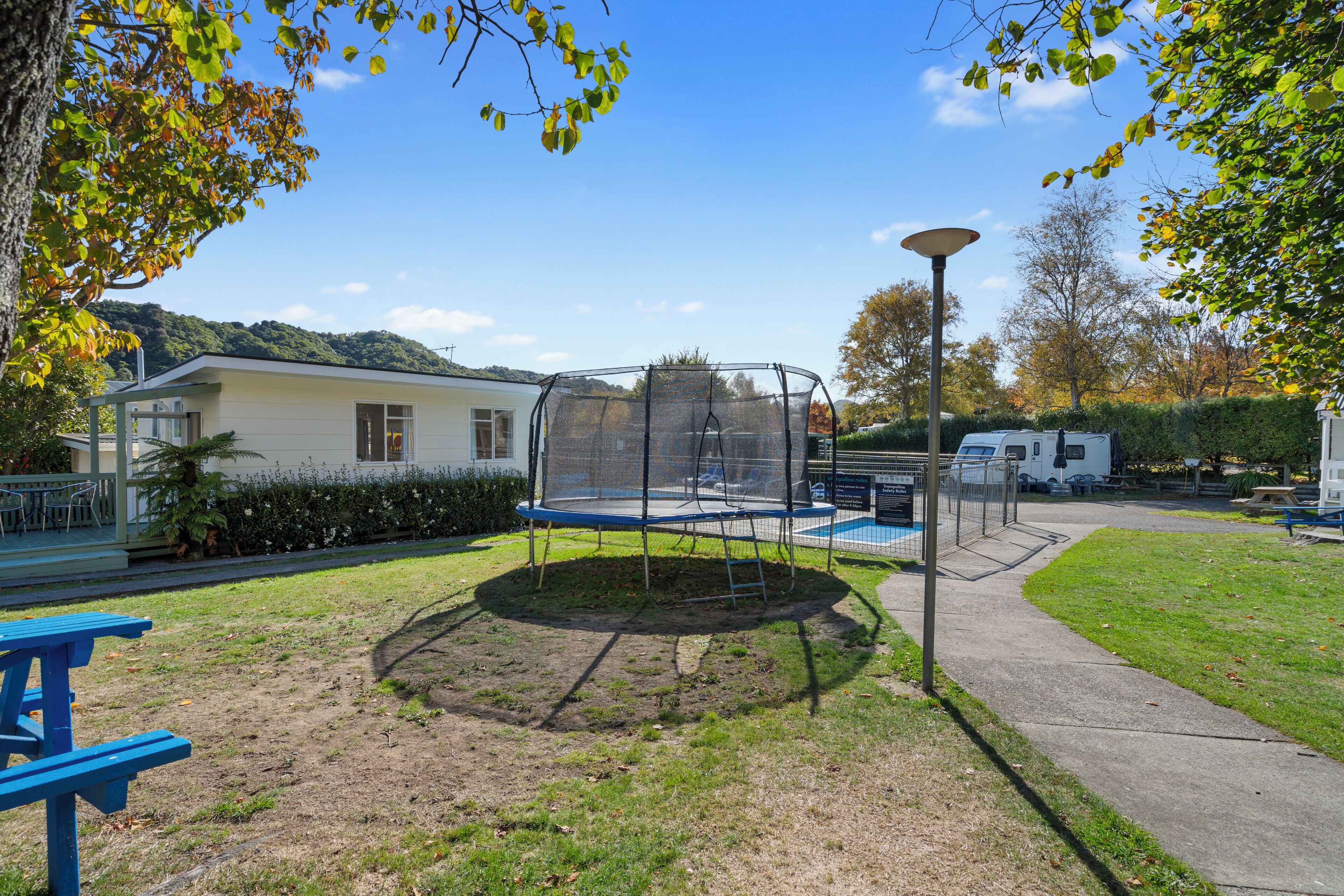 Une aire de jeux avec un trampoline et une table de pique-nique.