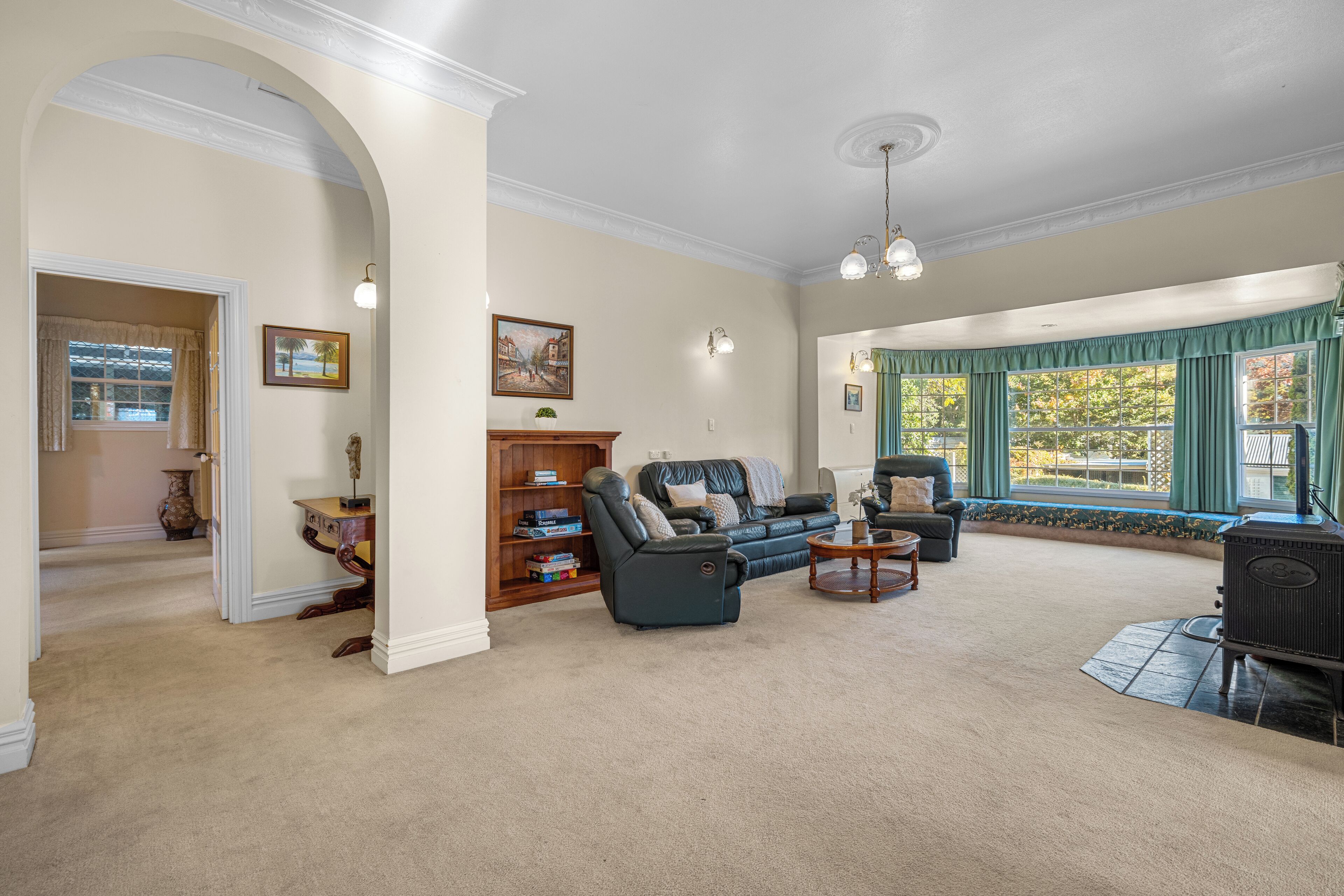 A spacious living room with a fireplace, a sofa set, and a large window with curtains.