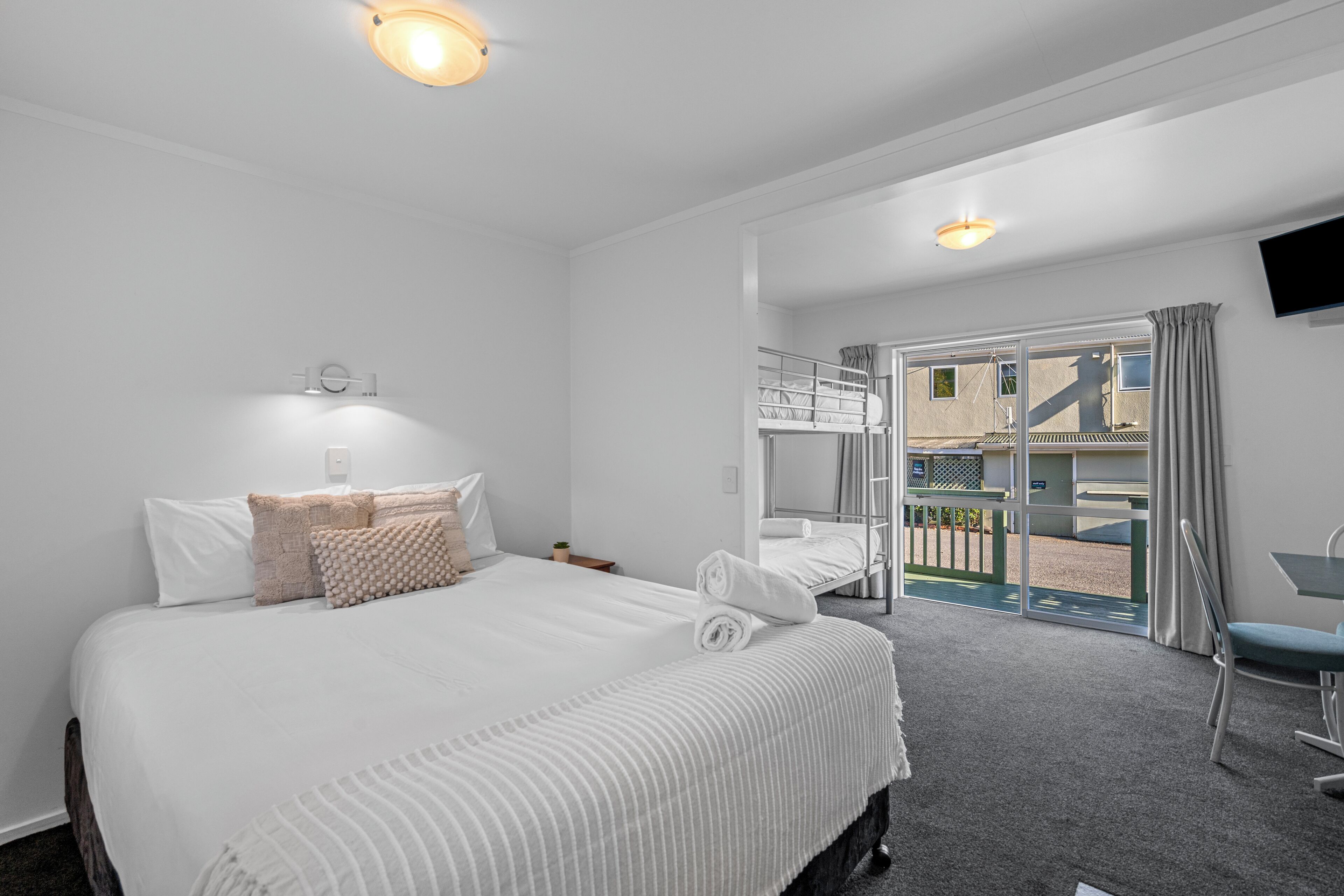 A hotel room with a large bed, a desk, and a balcony with a view.