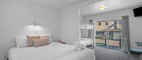 A hotel room with a large bed, a desk, and a balcony with a view.