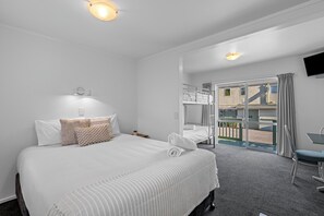 A hotel room with a large bed, a desk, and a balcony with a view. - Tasman Holiday Parks - Picton (Picton)