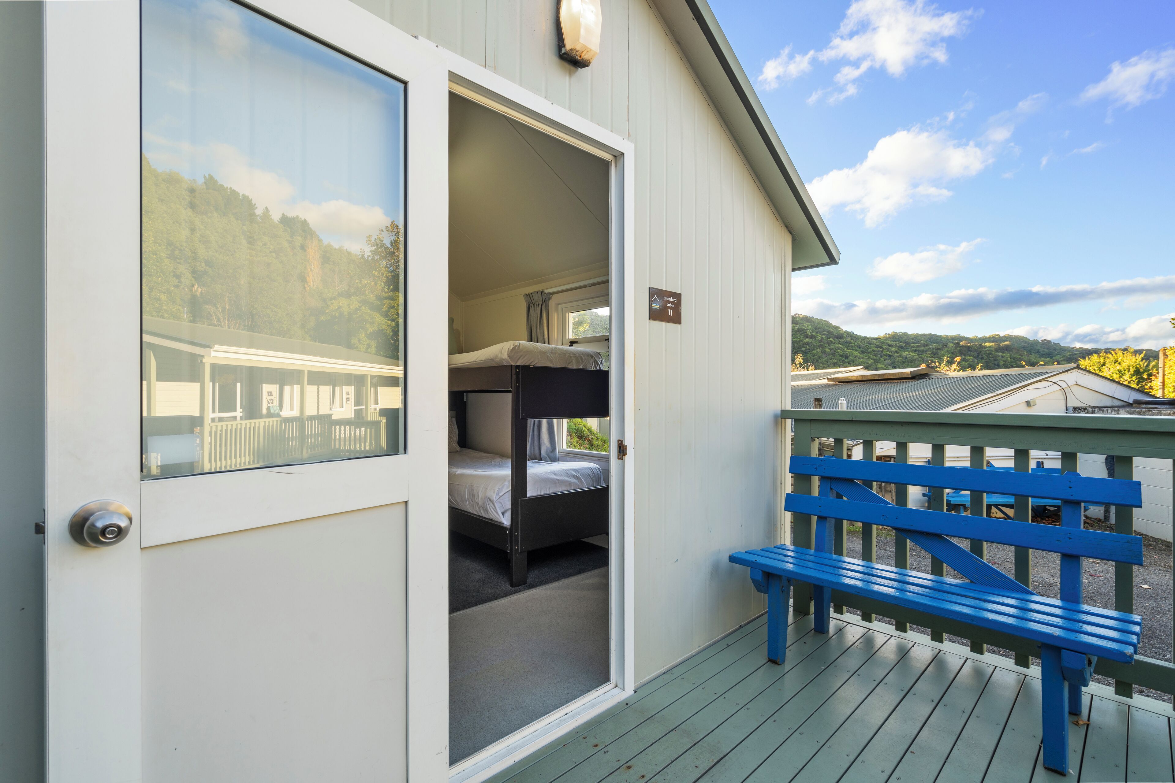 A room with bunk beds and a balcony with a blue bench.