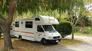 A white RV with the brand name 'Britz' parked under a tree.