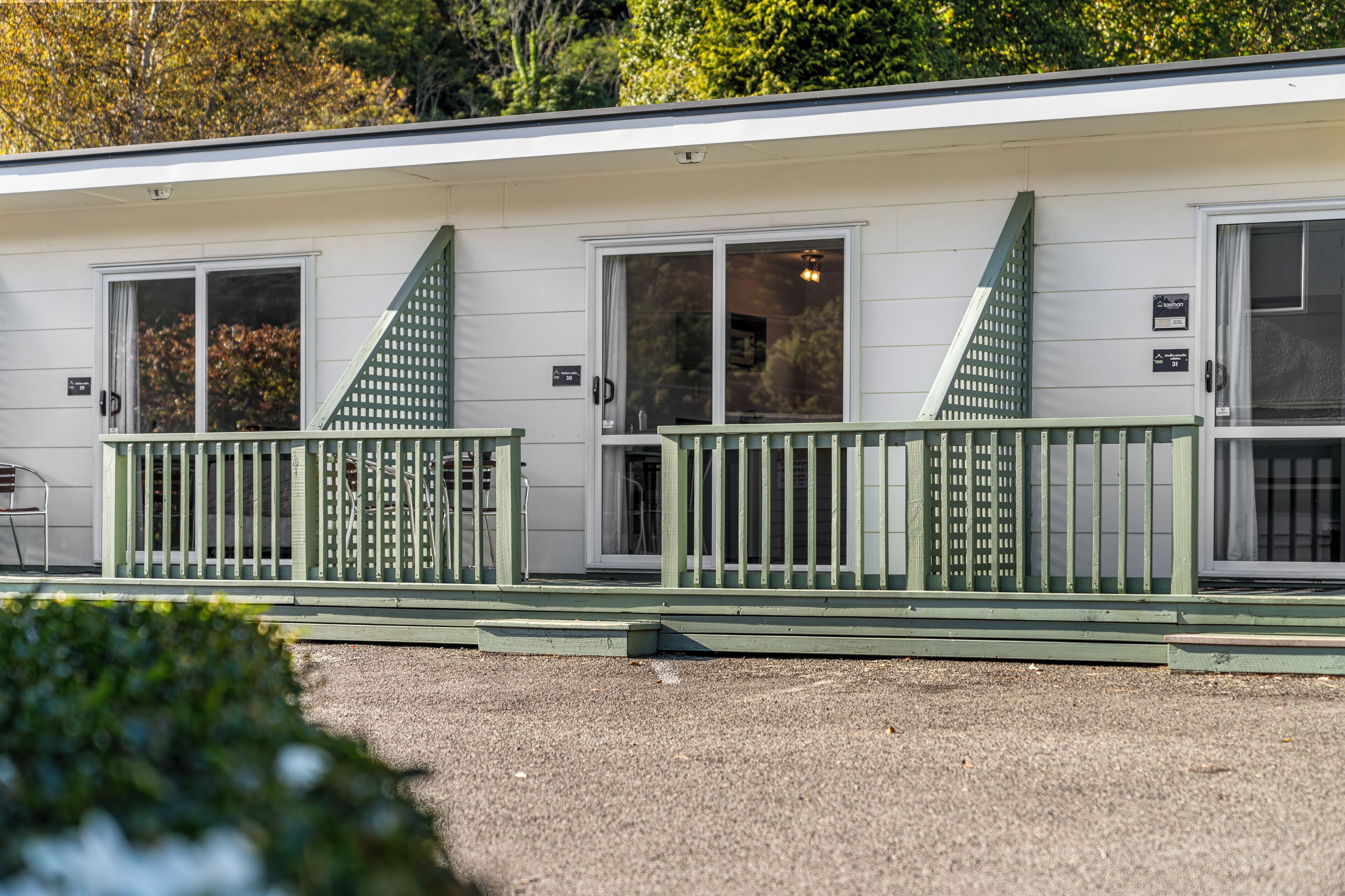 A single-story motel with a green porch and a covered outdoor seating area.