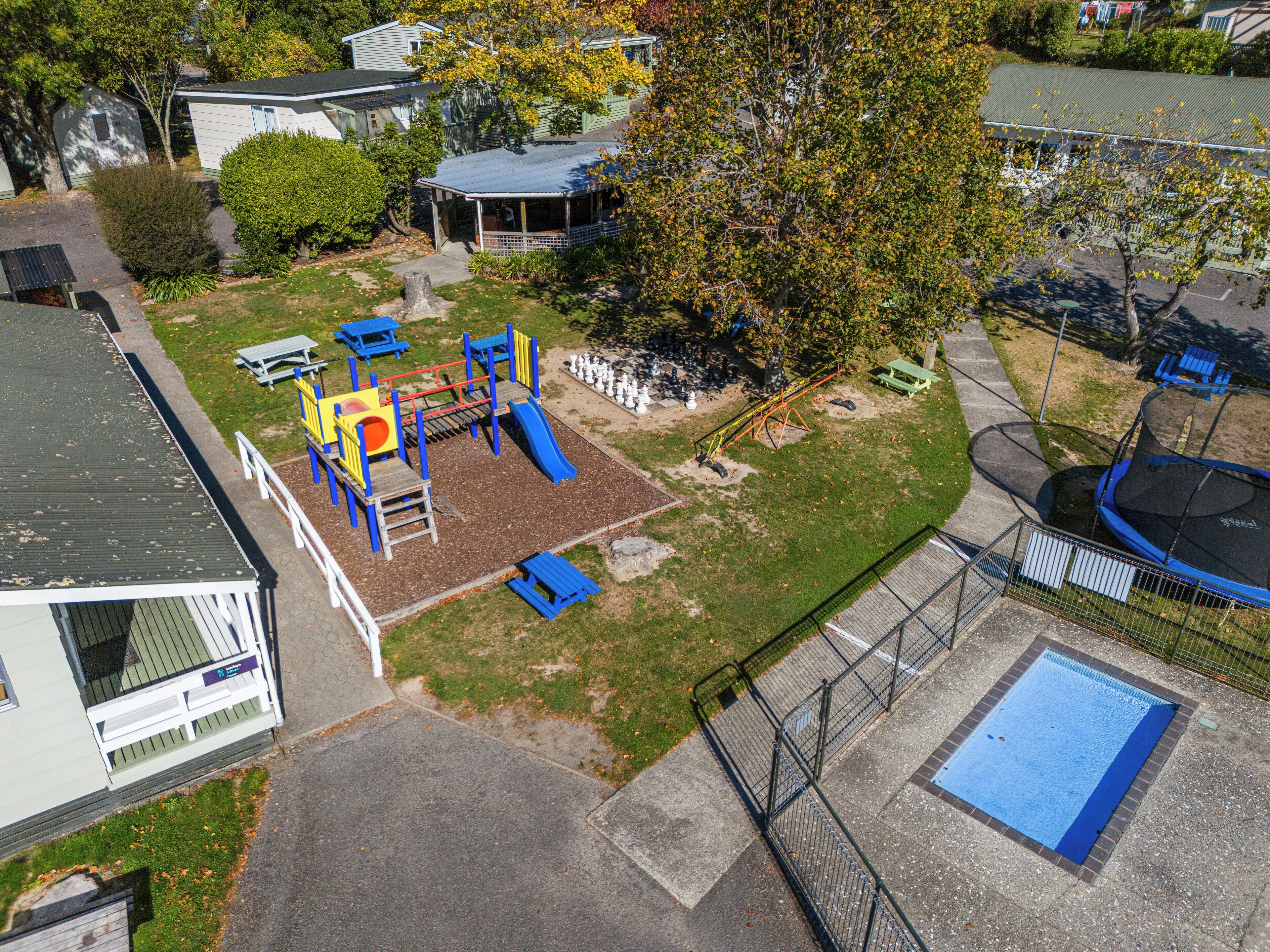 A playground with slides and climbing structures, a small pool, and a fenced area.