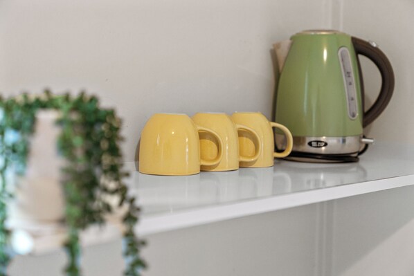 A kitchen counter with a green kettle and three yellow mugs. - Tasman Holiday Parks - Picton (Picton)