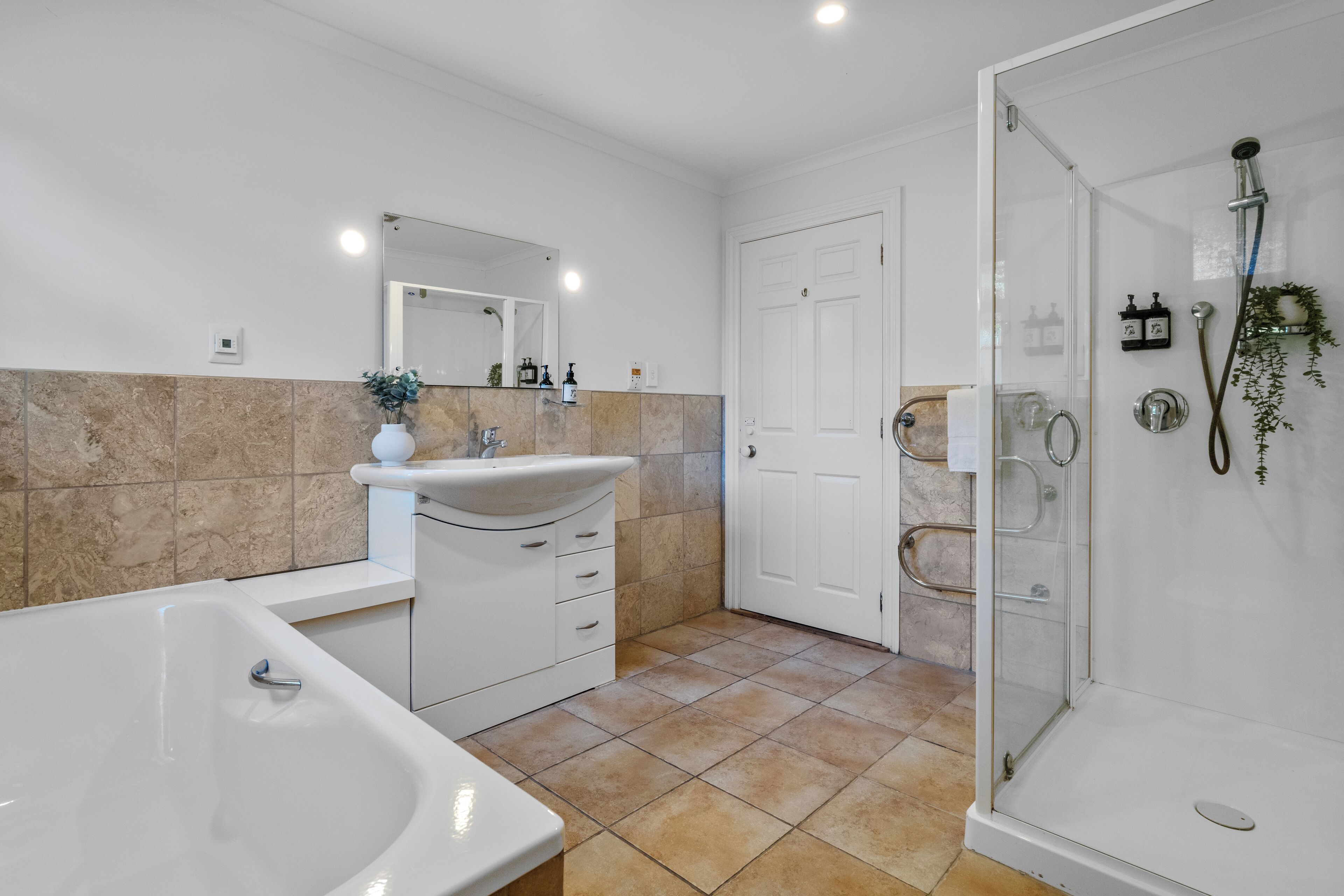 A modern bathroom with a bathtub, sink, and glass shower enclosure.