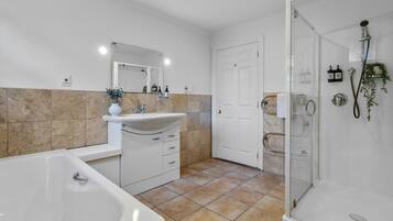 A modern bathroom with a bathtub, sink, and glass shower enclosure.