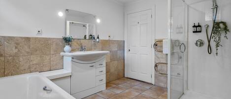 A modern bathroom with a bathtub, sink, and glass shower enclosure.