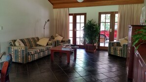 A living room with striped sofas, a wooden coffee table, and a large potted plant.
