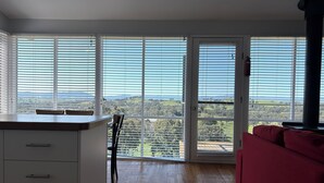 A spacious room with a large sliding glass door leading to a balcony, offering a scenic view of the countryside. - Burnt Creek Cottages Mansfield (Mansfield)
