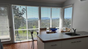 A modern kitchen with a large window, a blue bowl on the counter, and a wooden floor. - Burnt Creek Cottages Mansfield (Mansfield)
