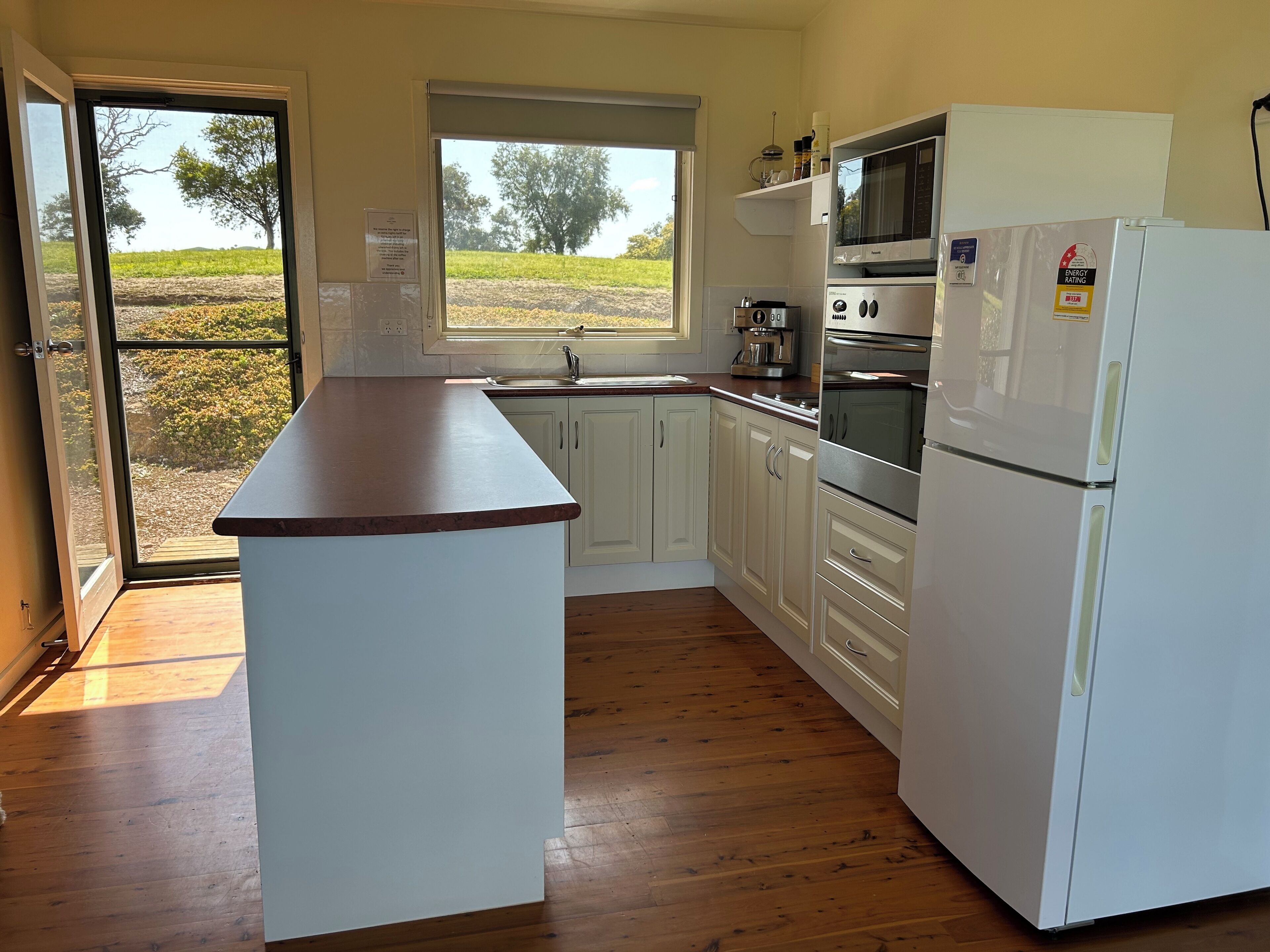 A kitchen with a central island, white cabinets, a stainless steel refrigerator, a microwave, and an oven.