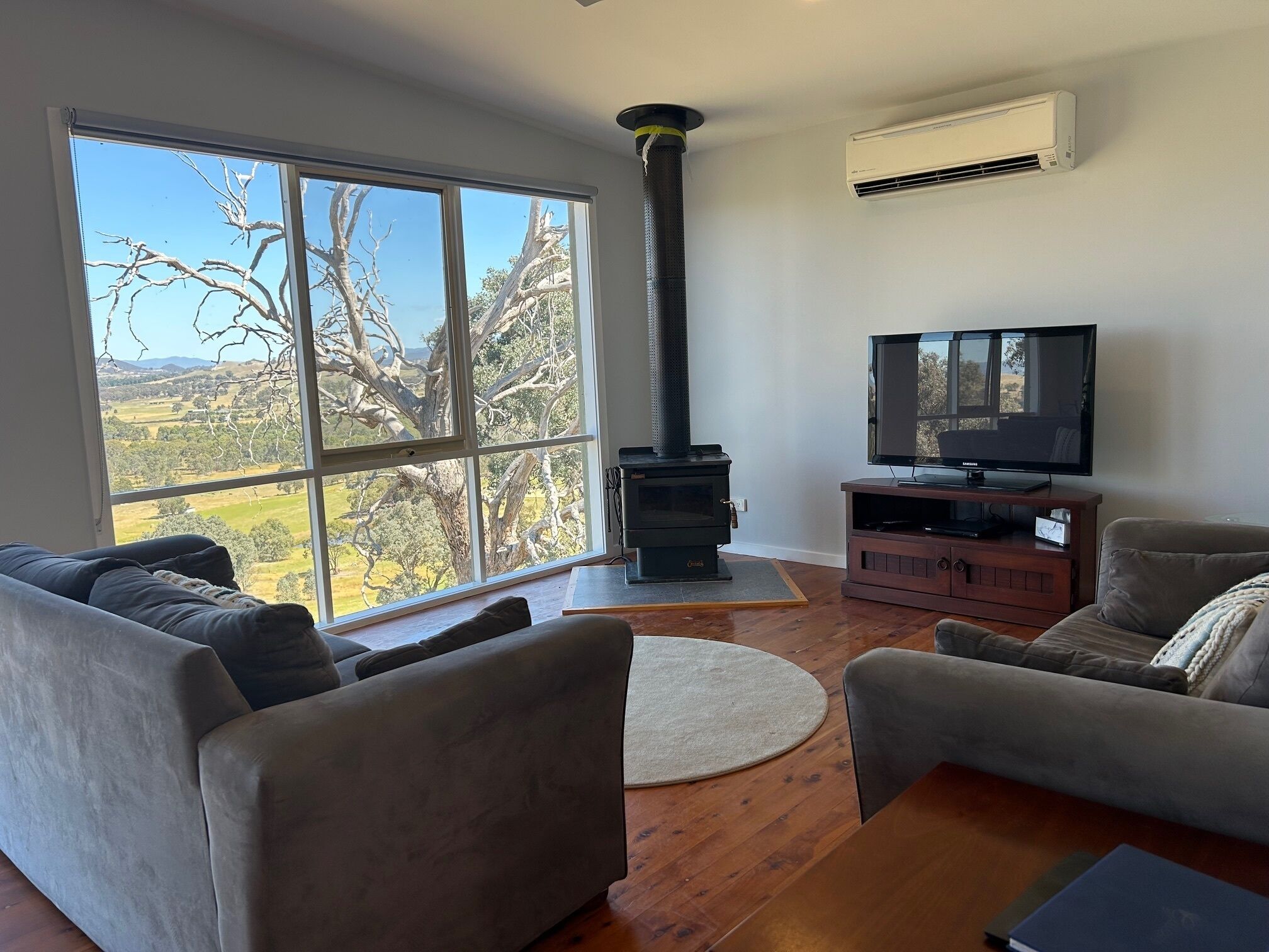 Una sala de estar con un ventanal grande, chimenea, televisor y dos sofás.