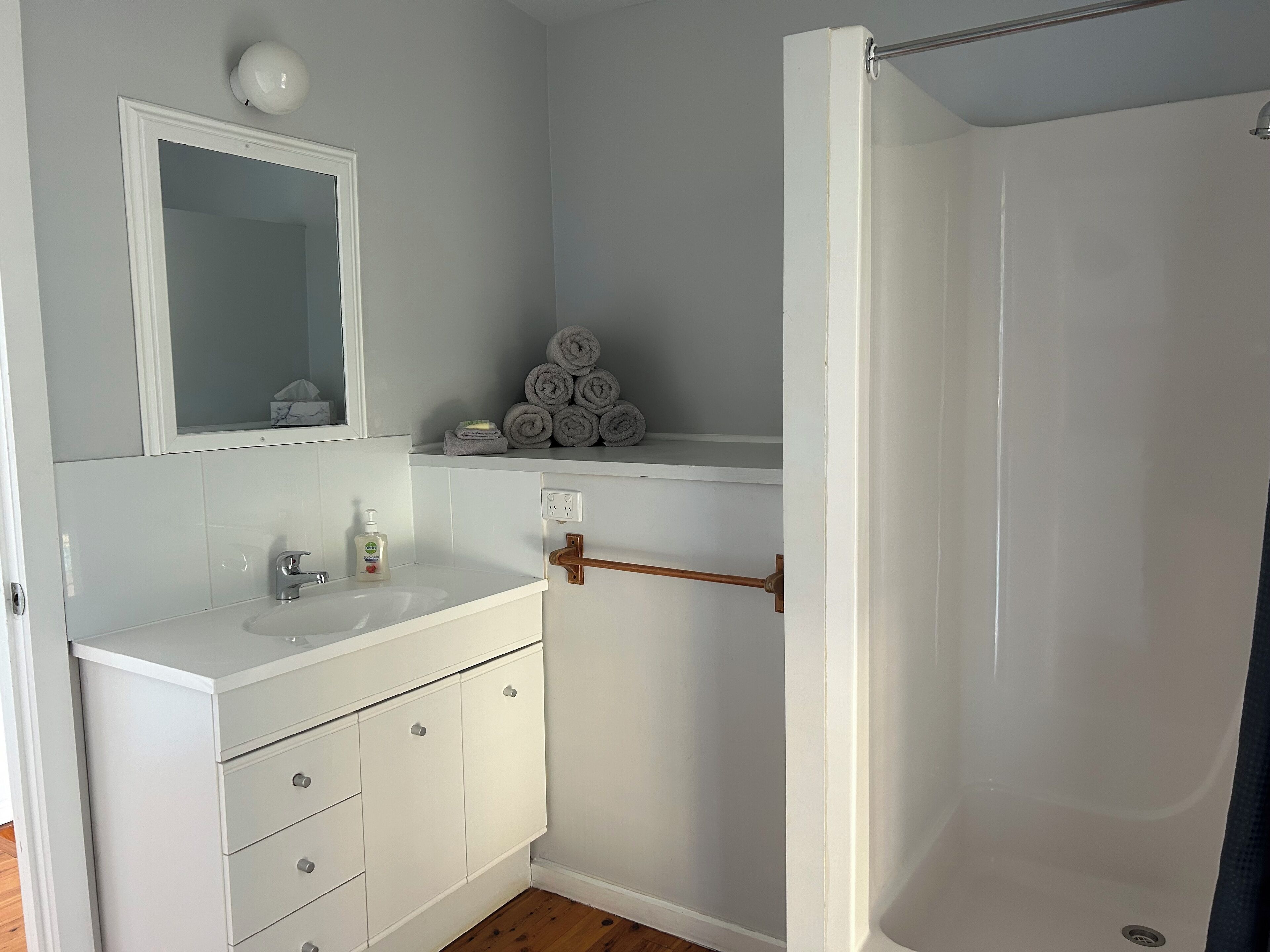 A bathroom with a white sink, mirror, and towel rack.
