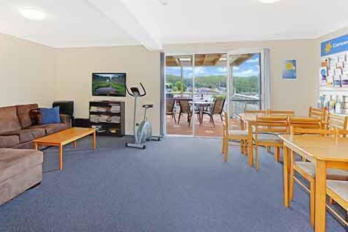 A living room with a sofa, coffee table, TV, exercise bike, and a dining area with chairs and a table.