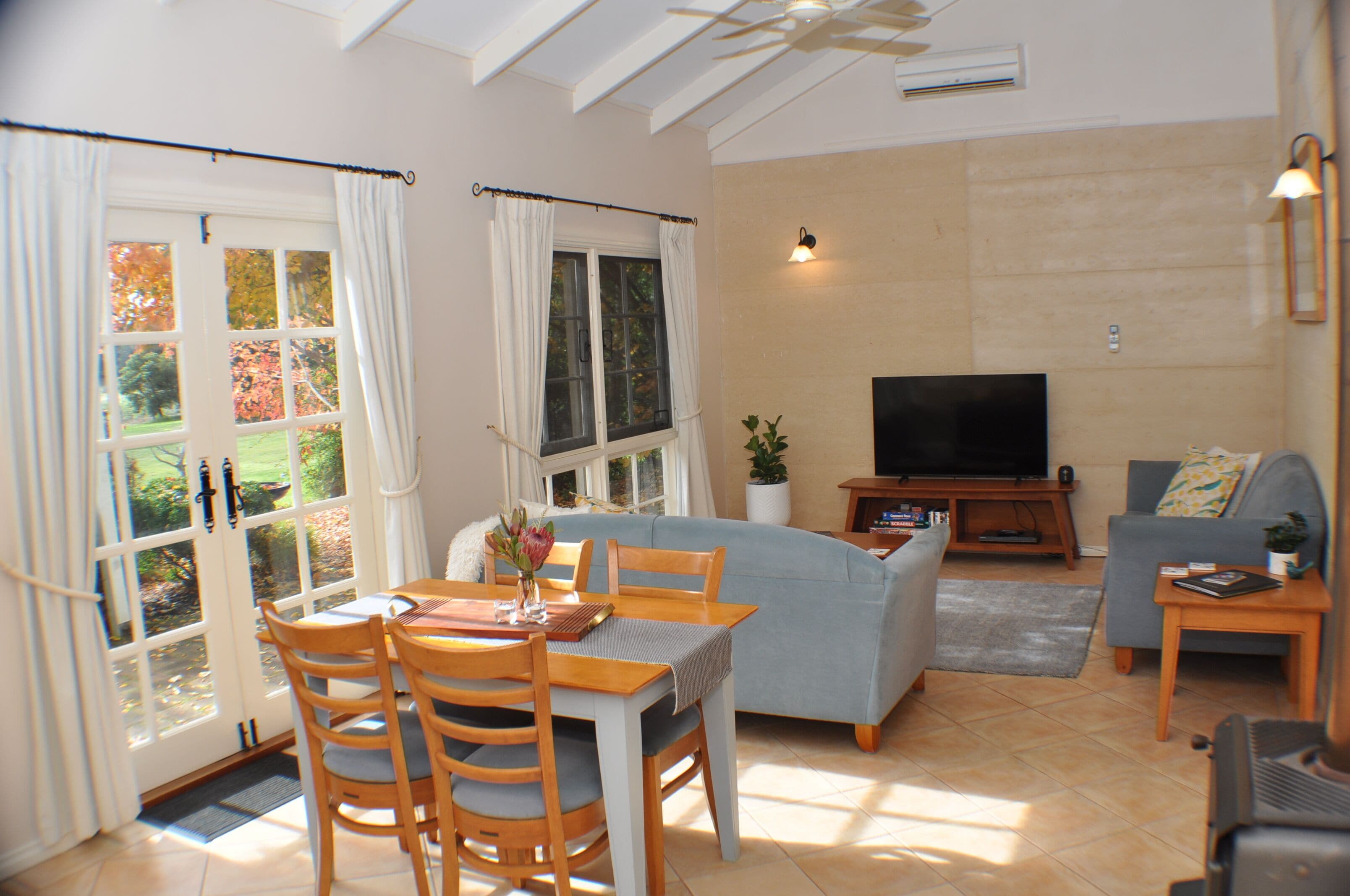 A living room with a dining area, a sofa, a TV, and a view of the outdoors.