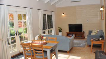 A living room with a dining area, a sofa, a TV, and a view of the outdoors.