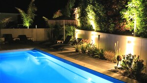 Una piscina con muelle de madera y sillones de descanso.
