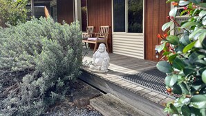 A wooden deck with a statue, a covered porch, and a window.