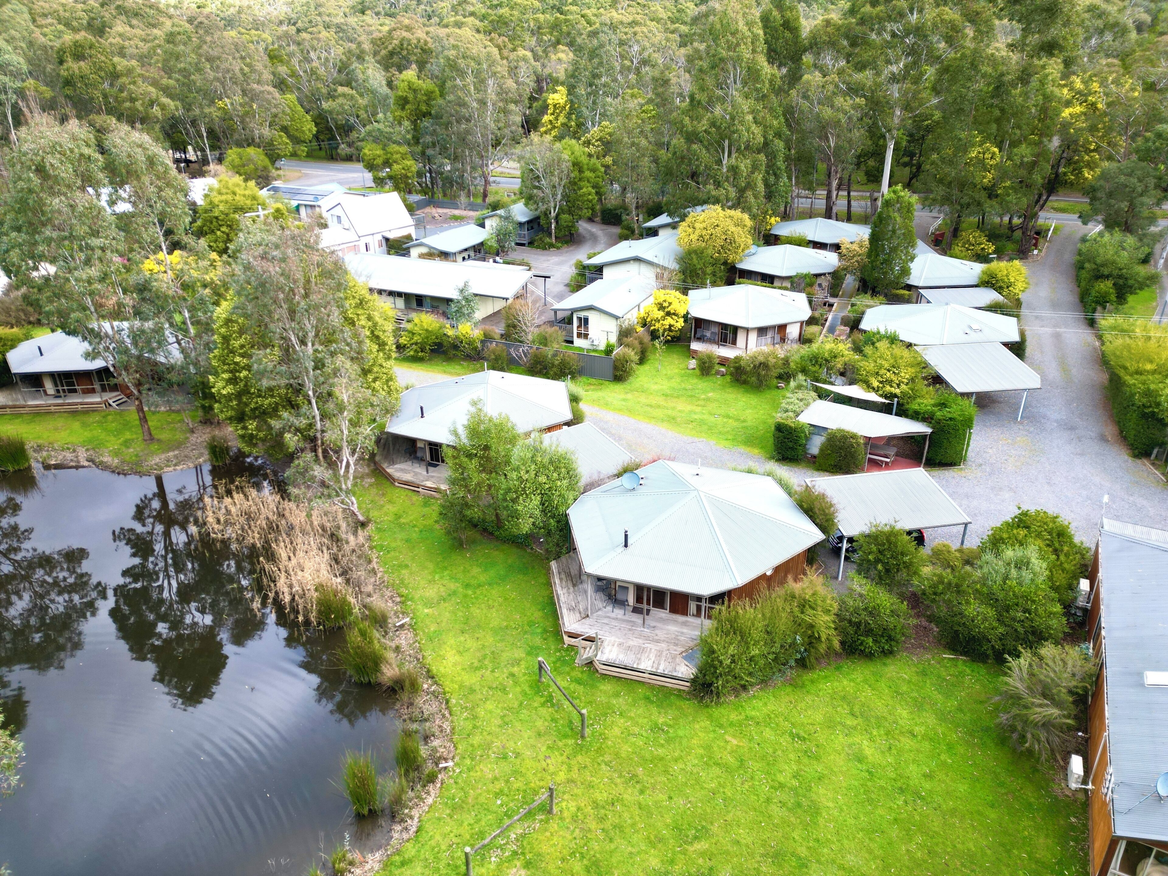 A residential area with multiple houses, a pond, and a road.