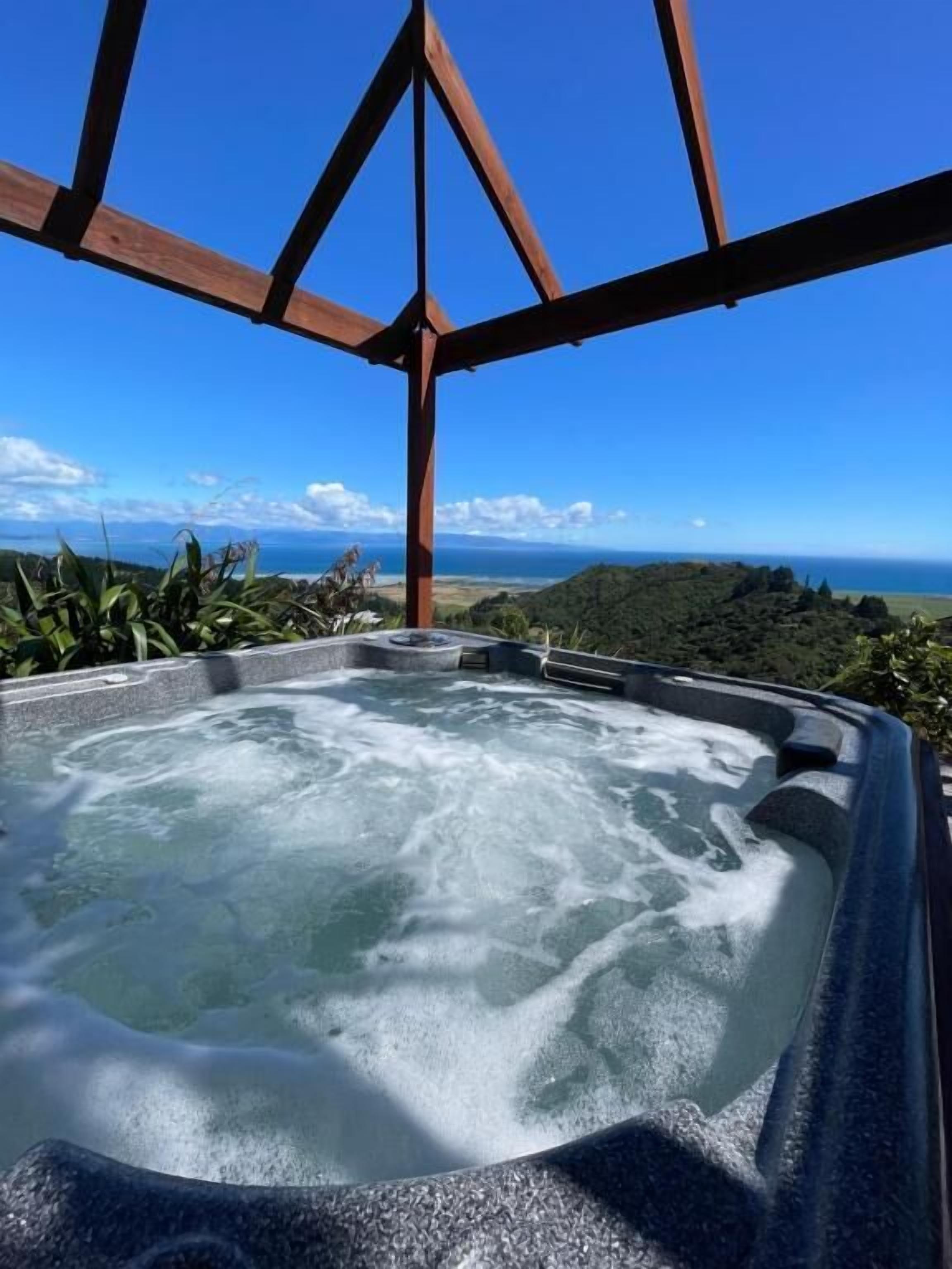 Un jacuzzi con vistas despejadas al océano y colinas al fondo.