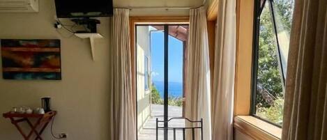 A room with a round table, chairs, a television, and a view of the outdoors.