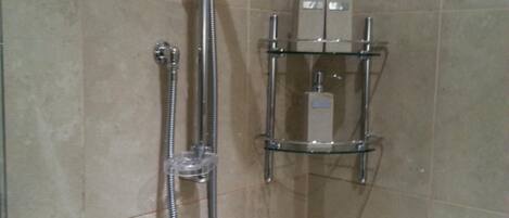 A shower with a handheld showerhead and a wall-mounted faucet.