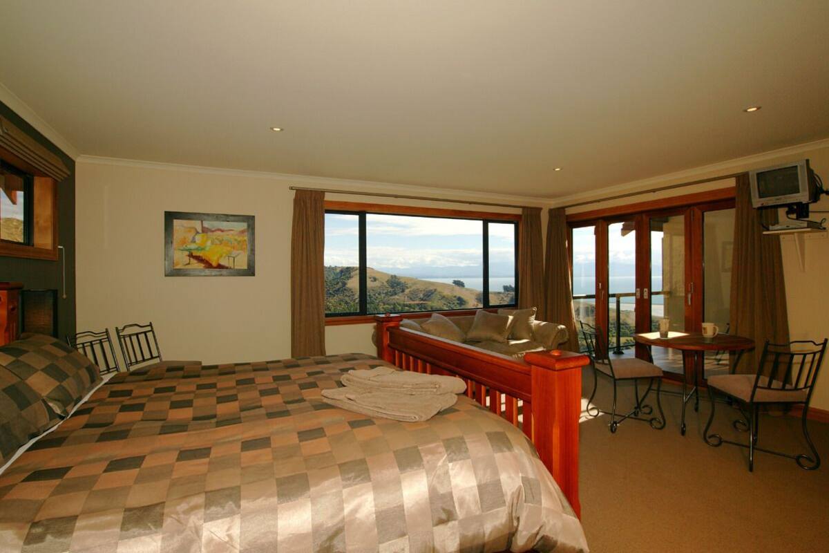 Habitación de hotel con una cama grande, un comedor y vistas a las colinas.