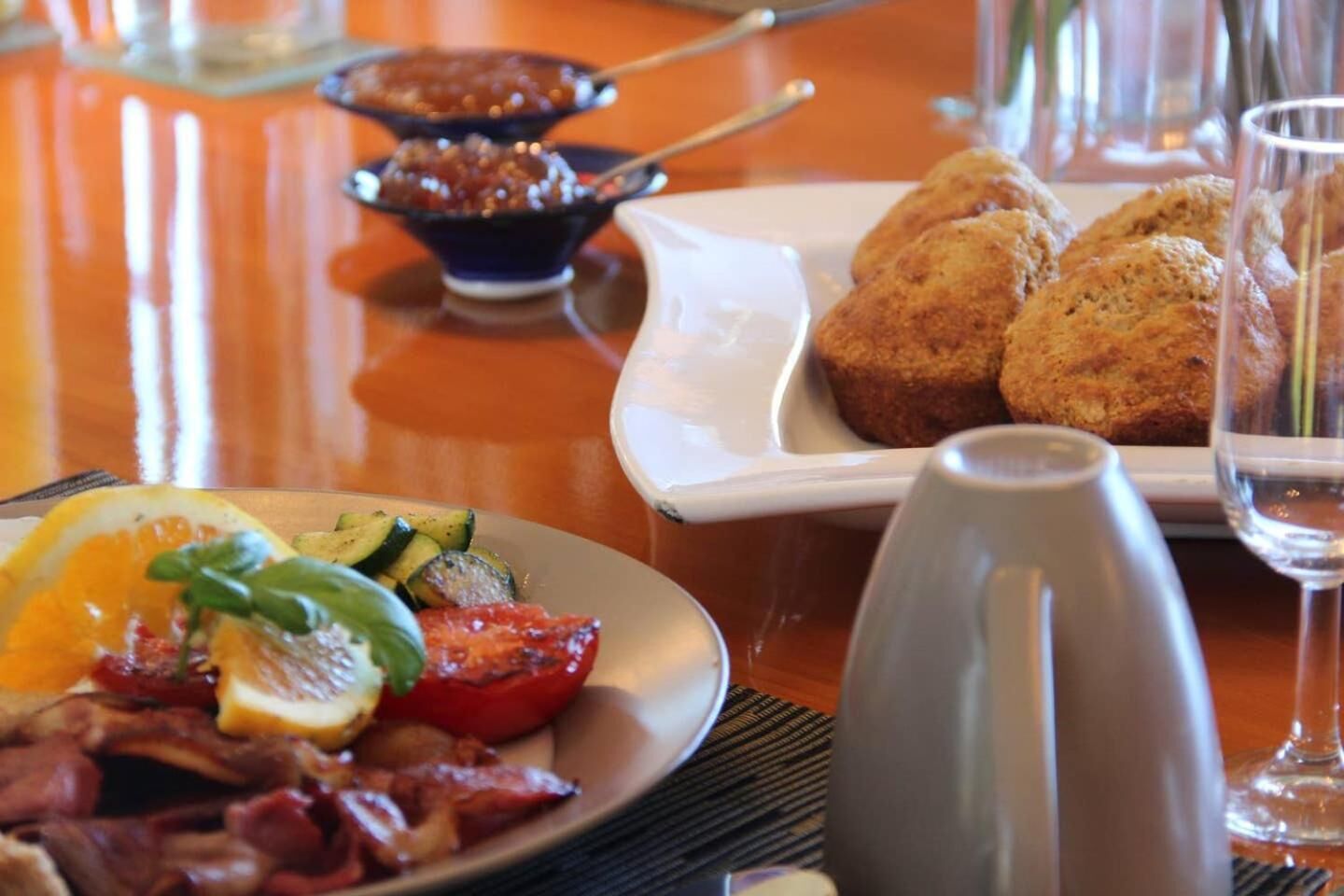 A breakfast setting with plates of food, a bowl of soup, and a glass of water.