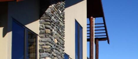 A modern house with a stone chimney, large windows, and a wooden deck.
