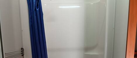 A bathroom with a white sink, a shower with a blue curtain, and a wooden floor.