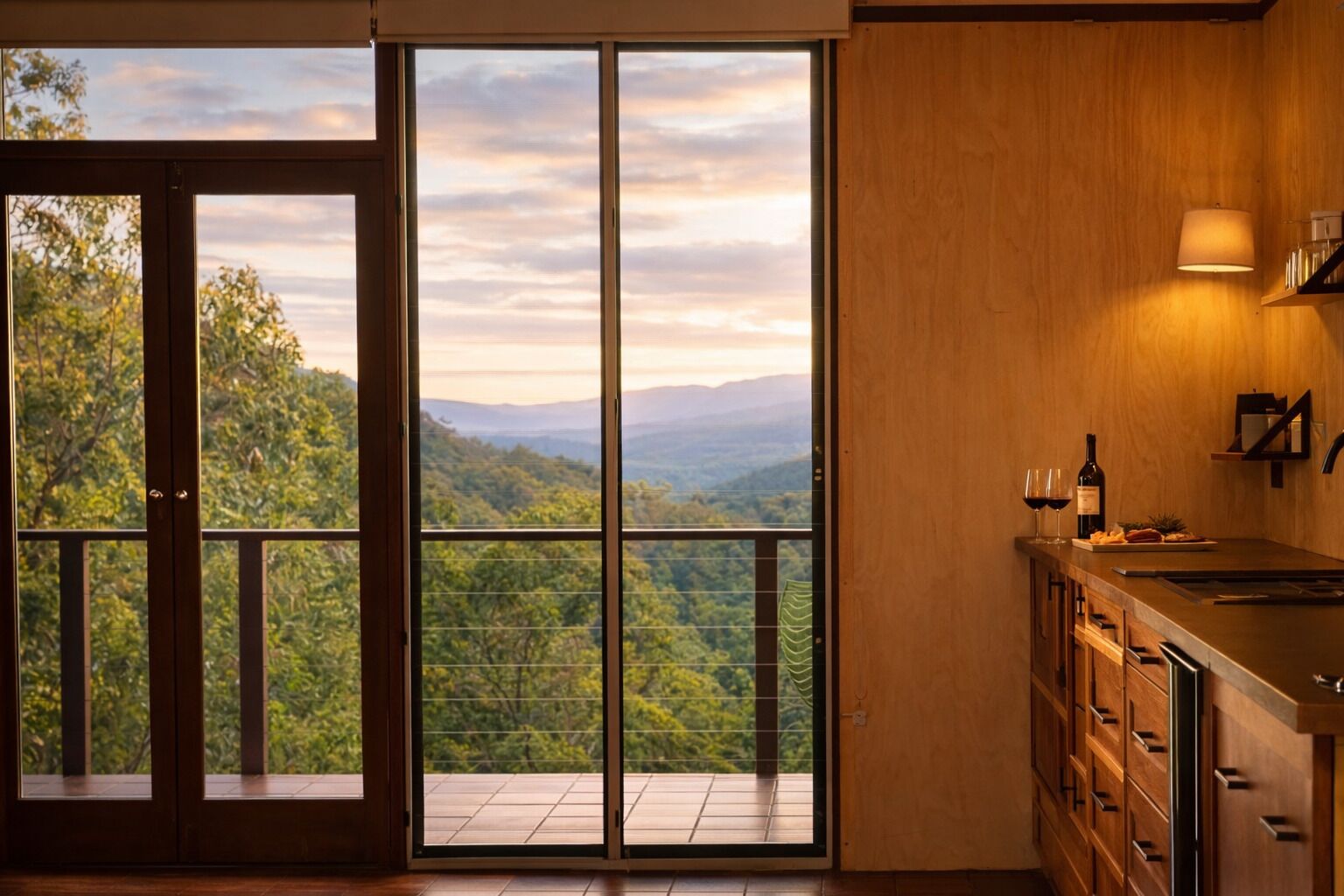 A kitchen with a view of a mountainous landscape through large glass doors.