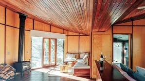 A spacious living area with a large wooden ceiling, a built-in fireplace, a sofa, and a dining table. - The Odd Frog (Bright)