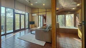 A spacious living area with a large window, a television, and a sofa. - The Odd Frog (Bright)