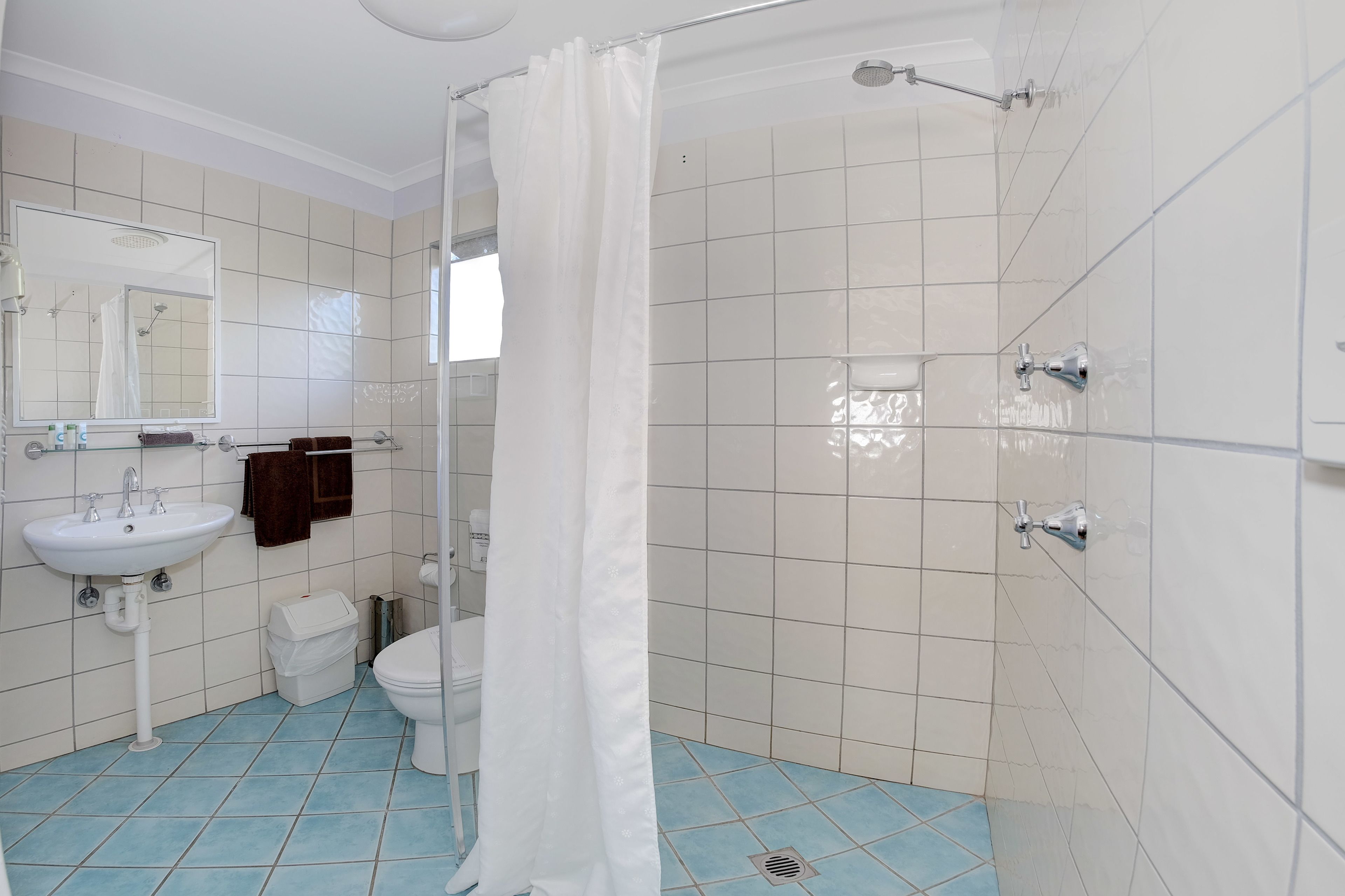A bathroom with a white sink, toilet, and shower area.