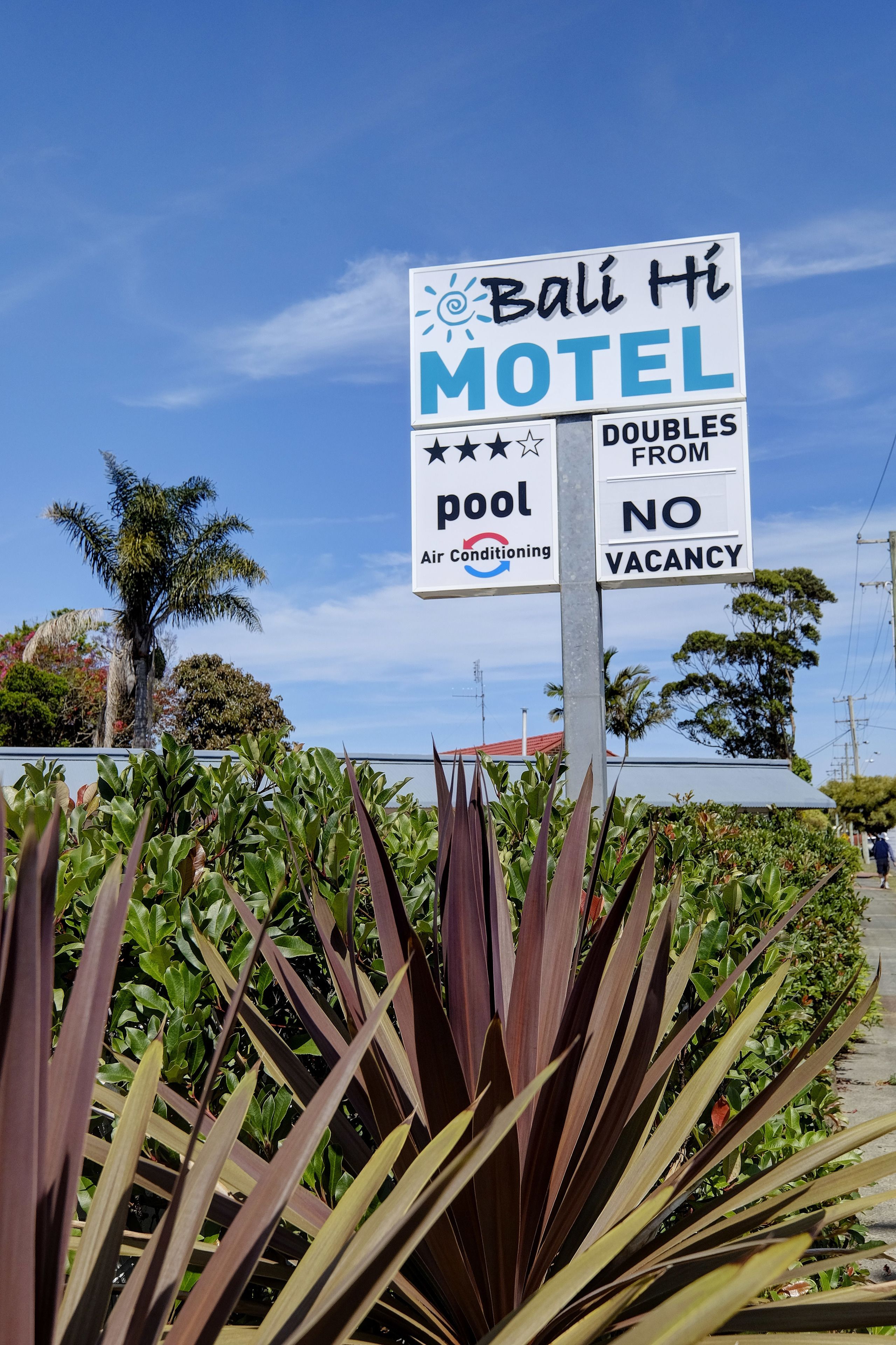 A sign for Bali Hi Motel advertising a pool and air conditioning, with a note that doubles are from no vacancy.
