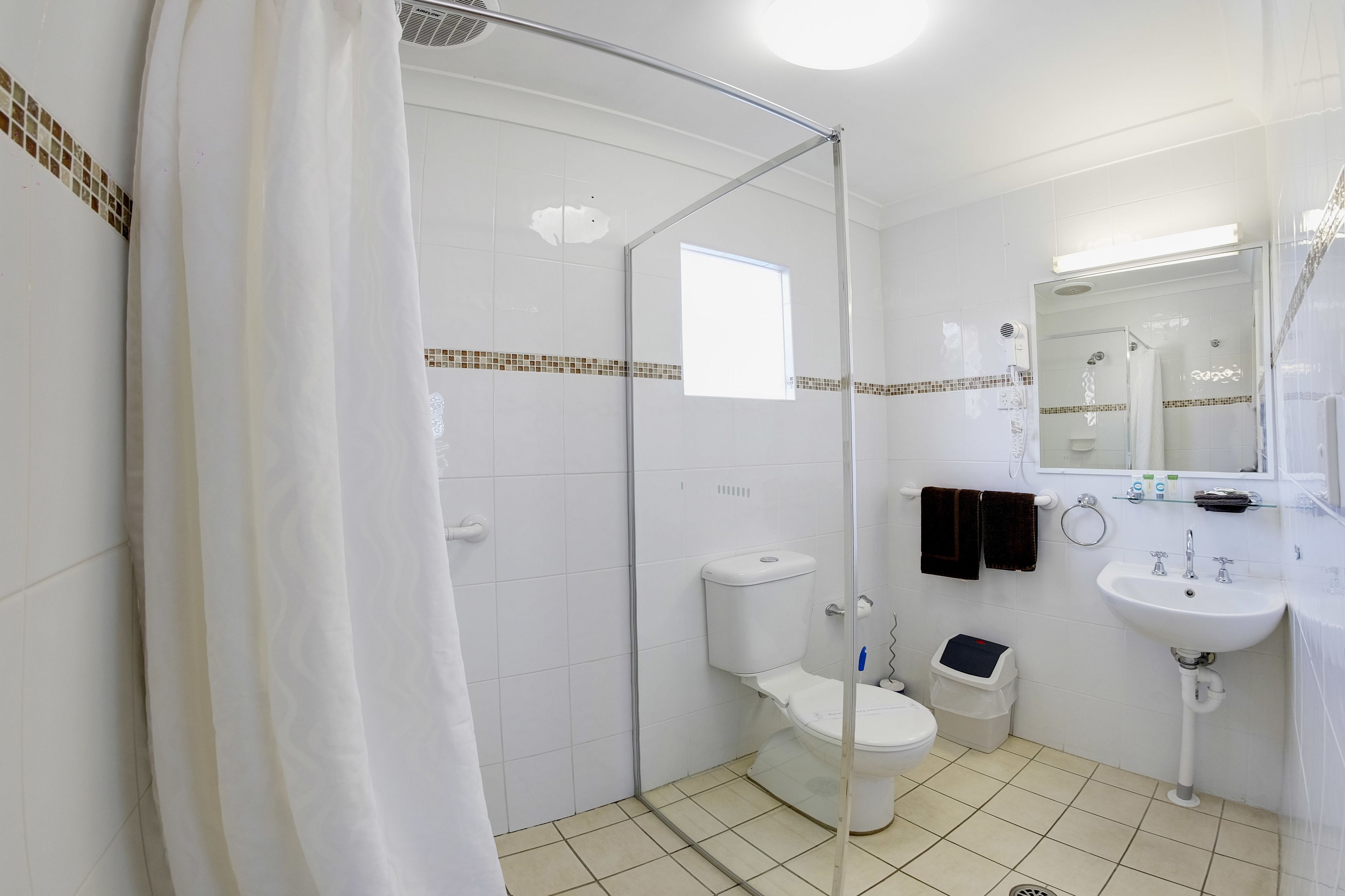 Um banheiro moderno com box de vidro, vaso sanitário, pia e espelho.