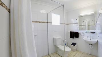 Um banheiro moderno com box de vidro, vaso sanitário, pia e espelho.