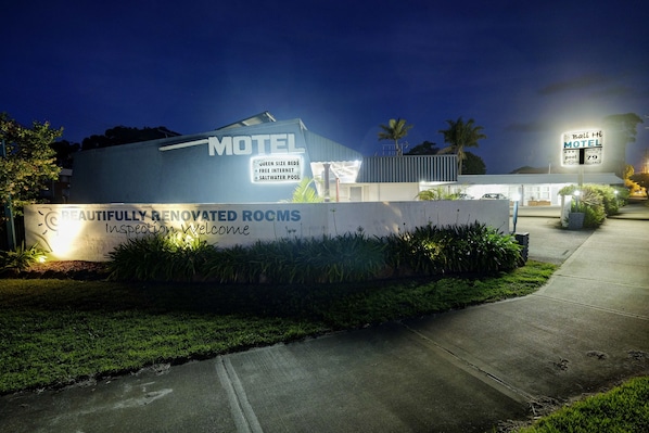A motel with a sign stating "Queen Size Beds, Free Internet, Saltwater Pool" and "Beautifully Renovated Rooms, Inspection Welcome".