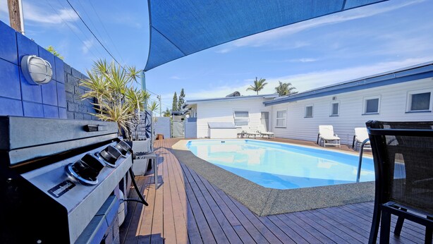 Un pati amb piscina, barbacoa i zona de seients a l'aire lliure.