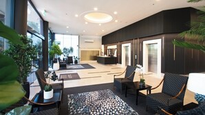 Un vestíbulo moderno con asientos, una recepción y ventanas amplias.