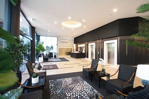 A modern lobby with seating, a reception desk, and large windows.