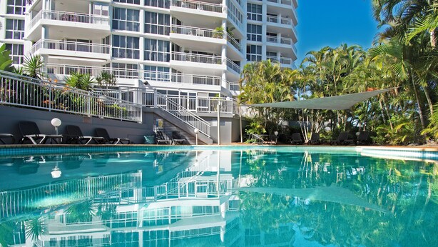 Un hotel con piscina, zona de estar al aire libre y un edificio de varios pisos.