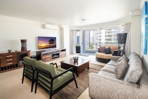 A living room with a sofa, chairs, a coffee table, and a TV.
