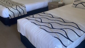A hotel room with two beds, each with a headboard, bedside tables, and lamps. - Deniliquin Country Club Motor Inn (Deniliquin)