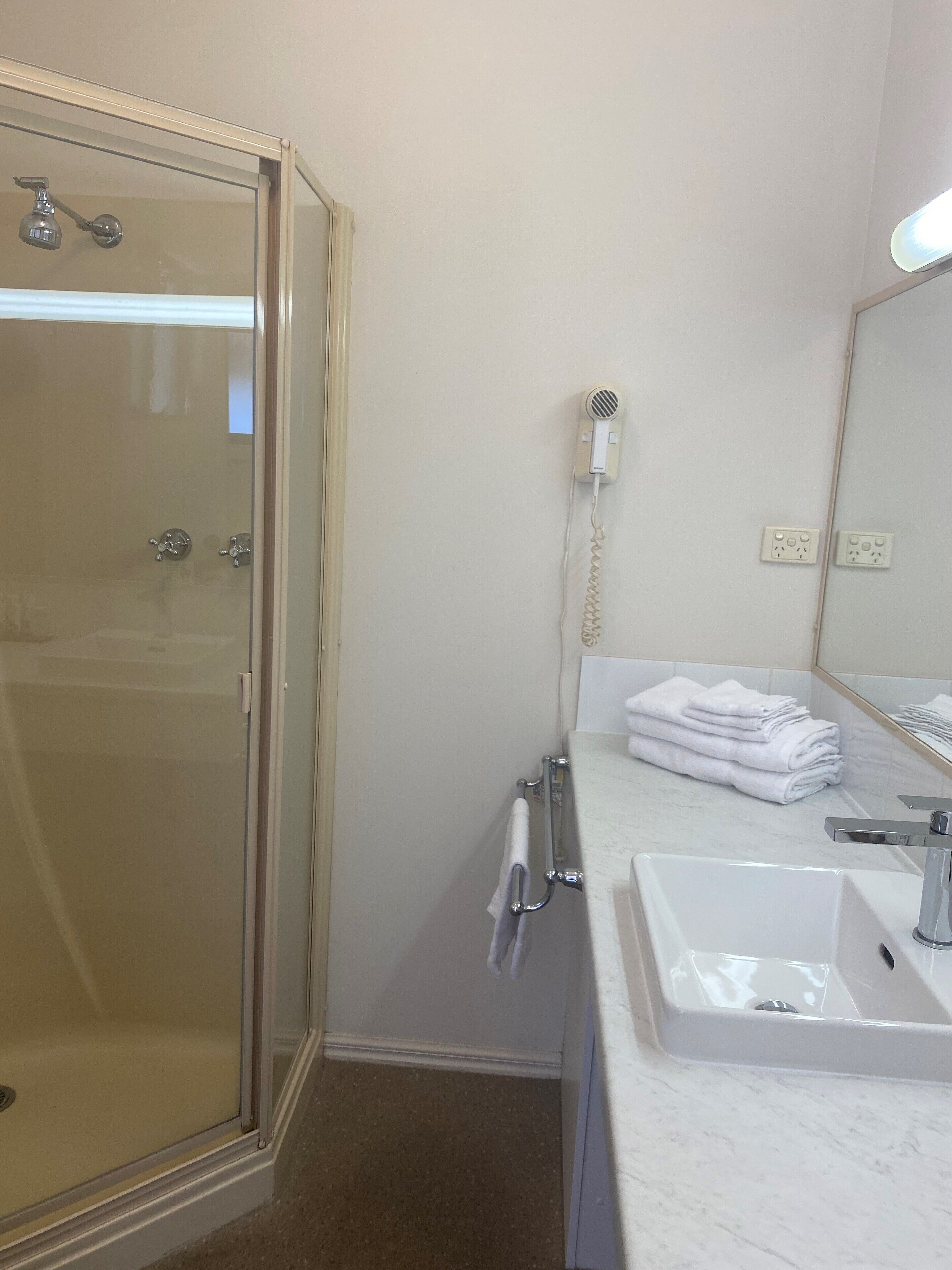 Een badkamer met een douche met glazen wanden, een witte wastafel en een handdoekhouder.