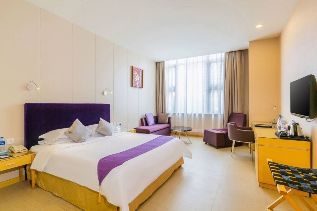 Una habitación de hotel con una cama grande, un escritorio, una silla y un televisor.
