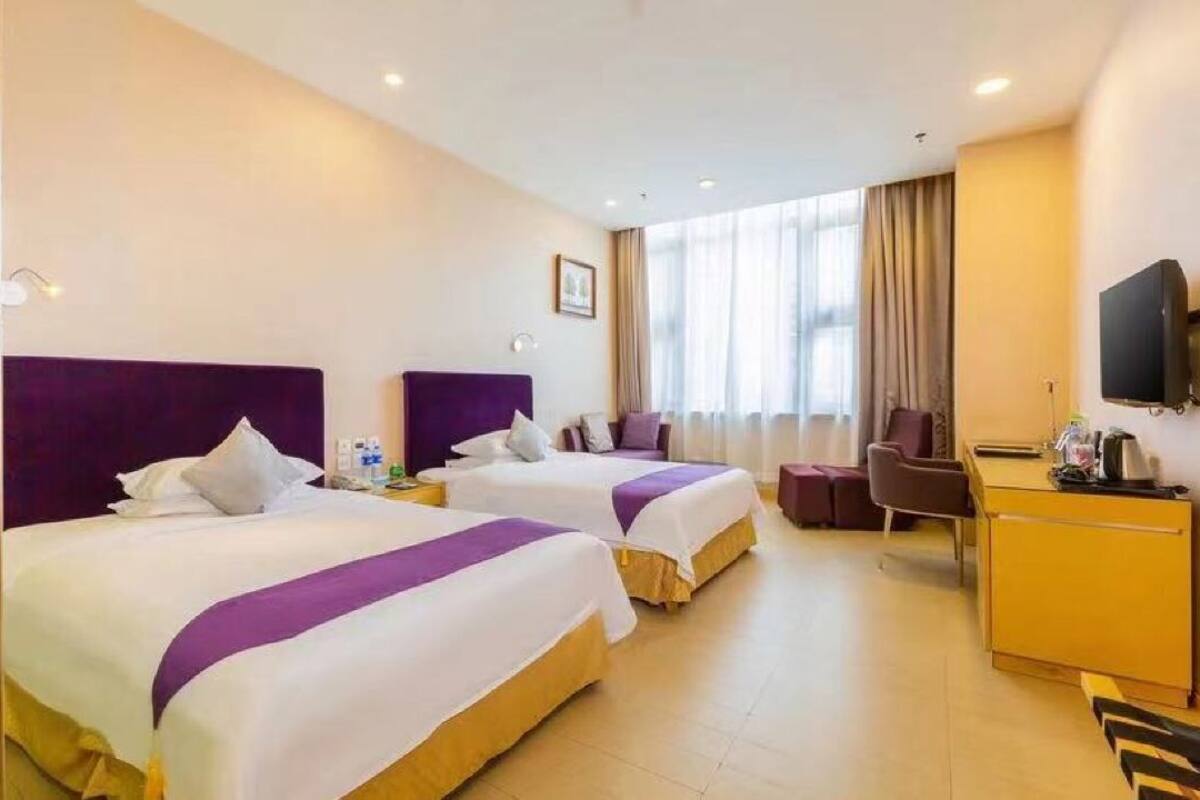 Habitación de hotel con dos camas, un escritorio, una silla y un televisor.